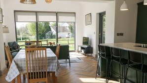 A modern kitchen with a bar area, wooden dining table, and chairs. - Corradillar Quay Cottage (Enniskillen)