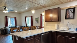 A modern kitchen with wooden cabinets, a marble countertop, and a built-in dishwasher.