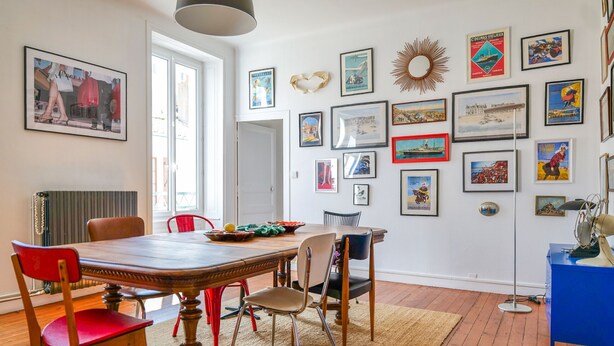 A dining area with a wooden table, red and beige chairs, and a variety of framed pictures on the walls. - Large apartment tastefully decorated for 5 people (Les Sables-d´Olonne)