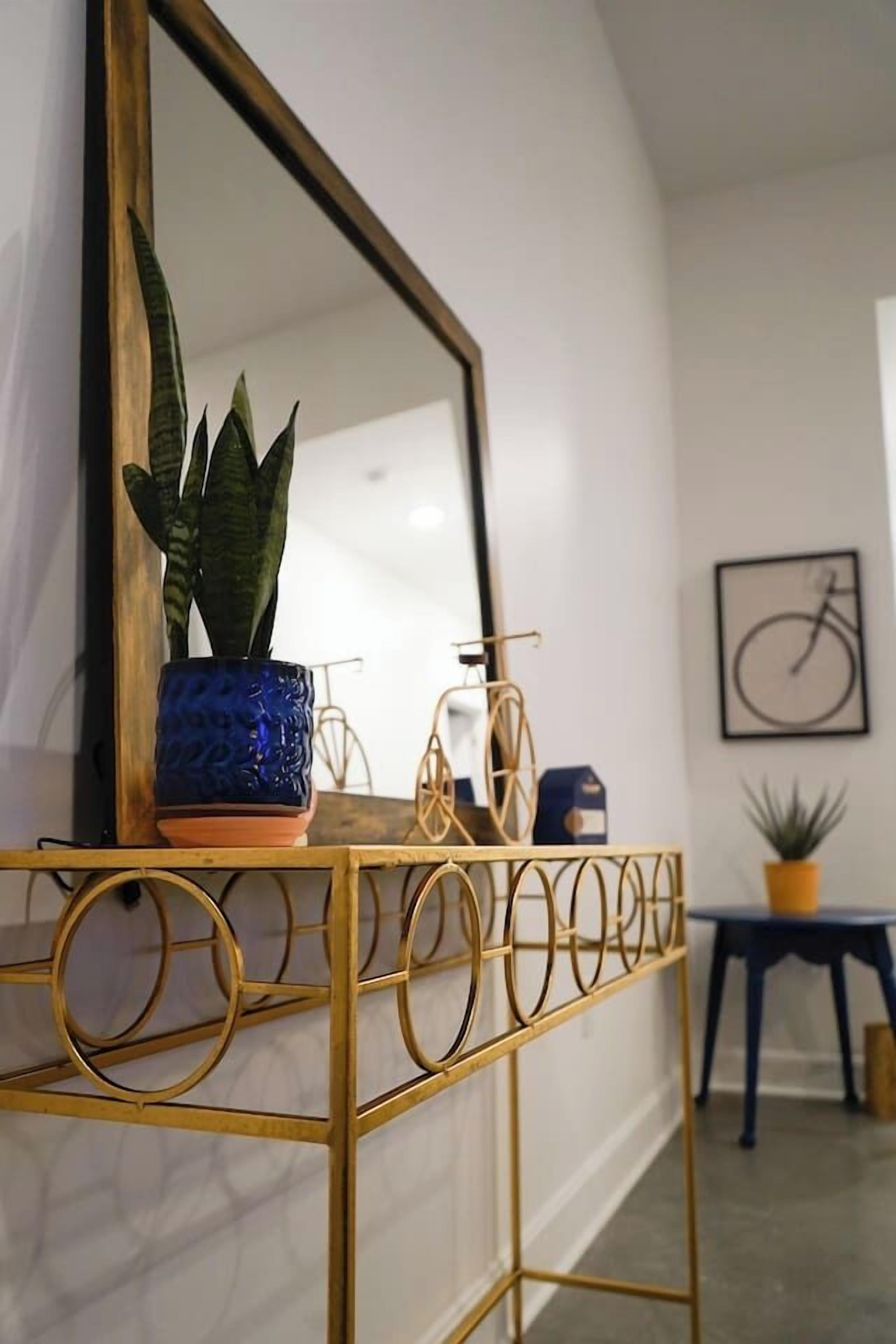 A gold-framed console table with a potted plant and a small white object.