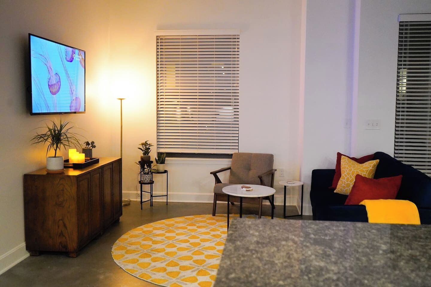 Un salon comprenant un téléviseur, un canapé, un fauteuil, une petite table et un meuble.
