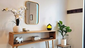 Een bijzettafeltje met een spiegel, boeken, een klein plantje en een decoratieve vaas.