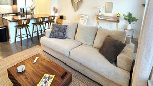 Een moderne woonkamer met een bank, salontafel en een plafondventilator.