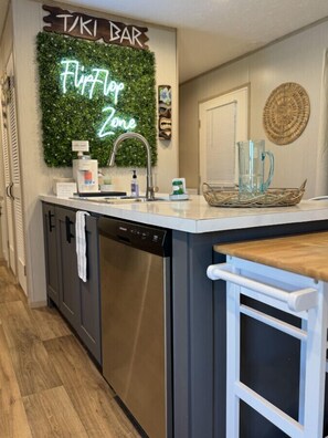 Enjoy cooking in this kitchen with a central island, stainless steel dishwasher, and white sink.