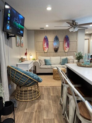 Relax in this stylish living space with a flat-screen TV, sofa, and wicker chair.