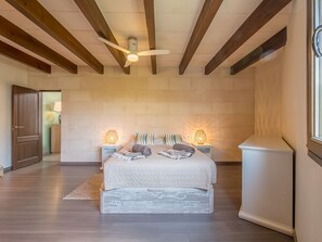 A bedroom with a bed, bedside lamps, a ceiling fan, and a window.