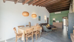Un área de comedor con una mesa y sillas de madera, un sofá y un tapete estampado.