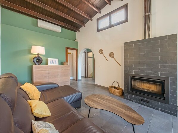 A living room with a fireplace, leather sofa, wooden coffee table, and a cabinet with decorative items.