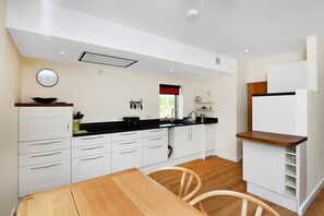 Una cocina moderna con armarios blancos, una mesa de comedor de madera y una encimera negra.