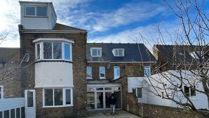 A two-story residential building with a modern design, featuring a flat roof, large windows, and a visible garage entrance. - NEW Immaculate Garden Flat (Cliftonville)
