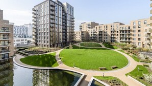A modern apartment complex with multiple high-rise buildings, a central circular green space, and a water feature.