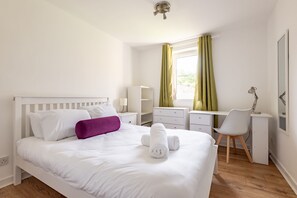 Ein ordentlich eingerichtetes Schlafzimmer mit einem Bett, einem Schreibtisch und einem Stuhl.