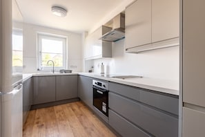 A modern kitchen with grey cabinets, a built-in oven, and a window providing natural light.