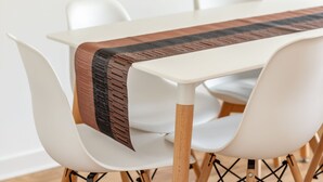 A modern dining table with a wooden runner, surrounded by white chairs with wooden legs. - Kate Kennedy Court (No 2) (St Andrews)