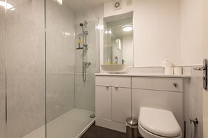 Ein modernes Badezimmer mit Duschkabine aus Glas, einem weißen Waschbecken und einer Toilette.