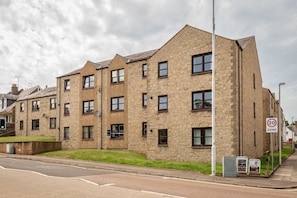 A multi-story residential building with a brick facade, multiple windows, and a 20 mph speed limit sign.