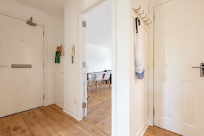 A hallway with wooden flooring, white doors, and a dining area visible through an open door. - Kate Kennedy Court (No 2) (St Andrews)