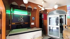 Un'area reception con interni in legno, una scrivania della reception, una ventola a soffitto e una porta in vetro che dà su un'altra stanza.