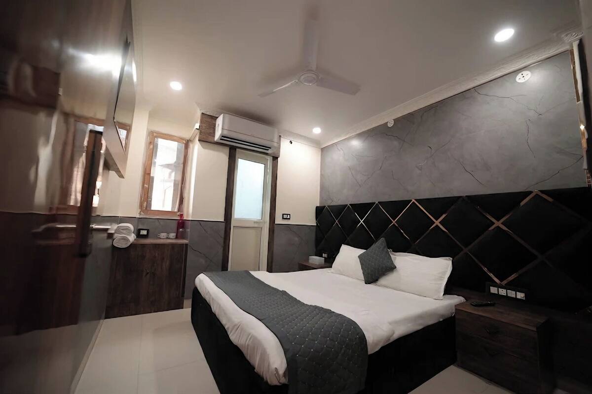 Quarto moderno com cama, mesas de cabeceira, espelho e ventilador de teto.