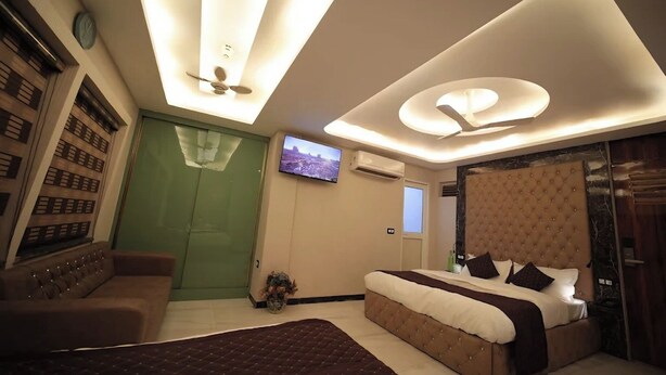 Una moderna camera d'albergo con un letto grande, un divano, una televisione e una porta verde.