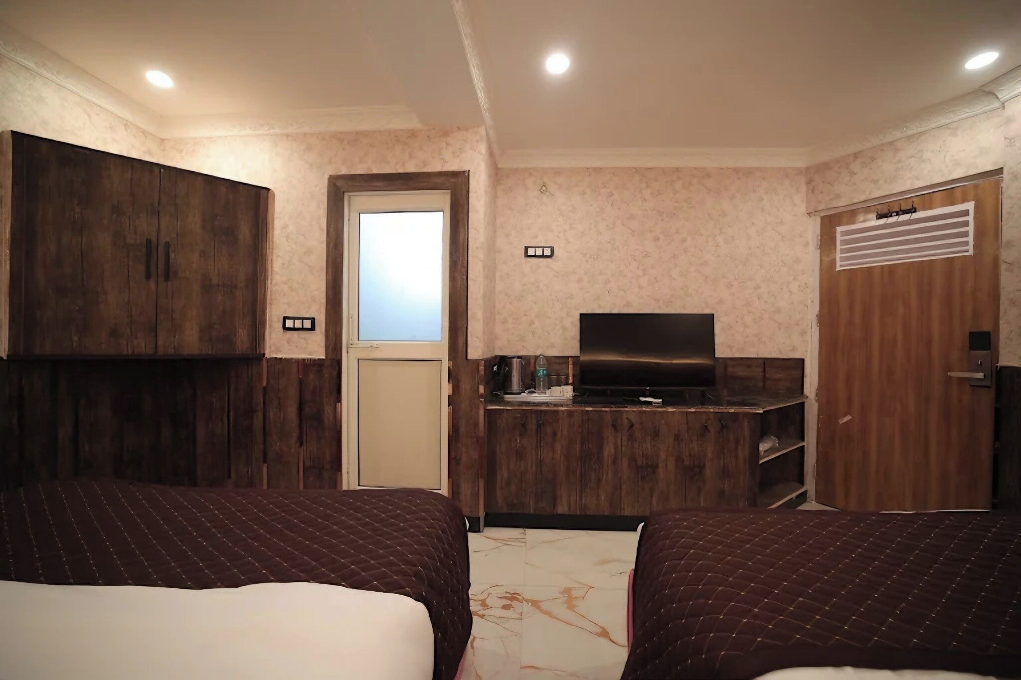 Una camera d'albergo con due letti, angolo cottura, televisione e armadio.