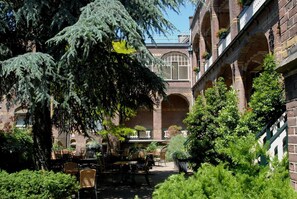 Guests can dine al fresco amidst lush greenery and historic architecture.