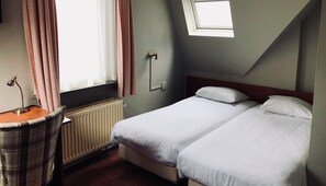 Cozy retreat with a single bed, bedside table, and lamp, offering a comfortable space to rest.