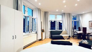 Un dormitorio moderno con una cama grande, un área de descanso con un sofá y sillas, y una mesa de comedor.