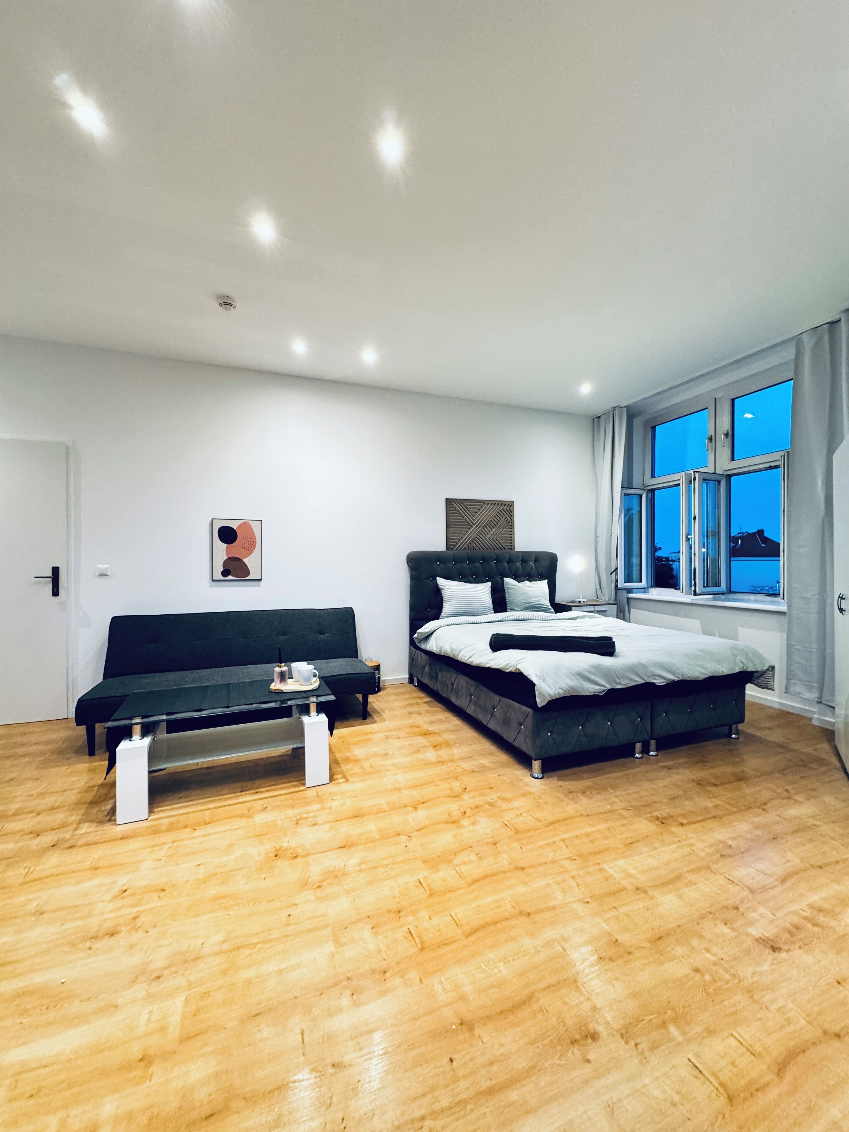 A modern bedroom with a bed, a sofa, and a coffee table.