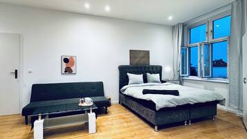 A modern bedroom with a bed, a sofa, and a coffee table.