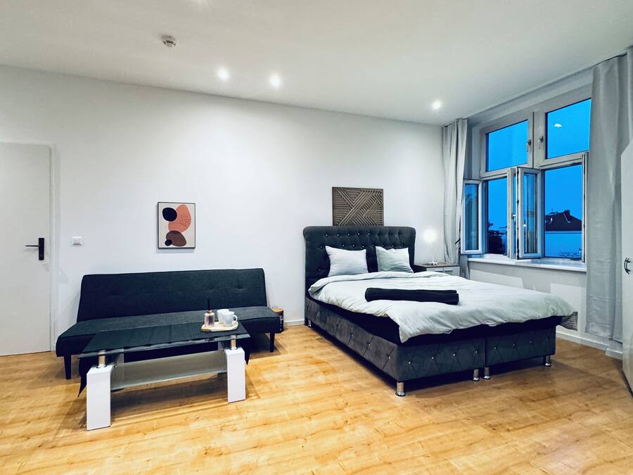 A modern bedroom with a bed, a sofa, and a coffee table.