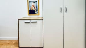 Una habitación con un armario blanco, un pequeño aparador con espejo y suelo de madera.