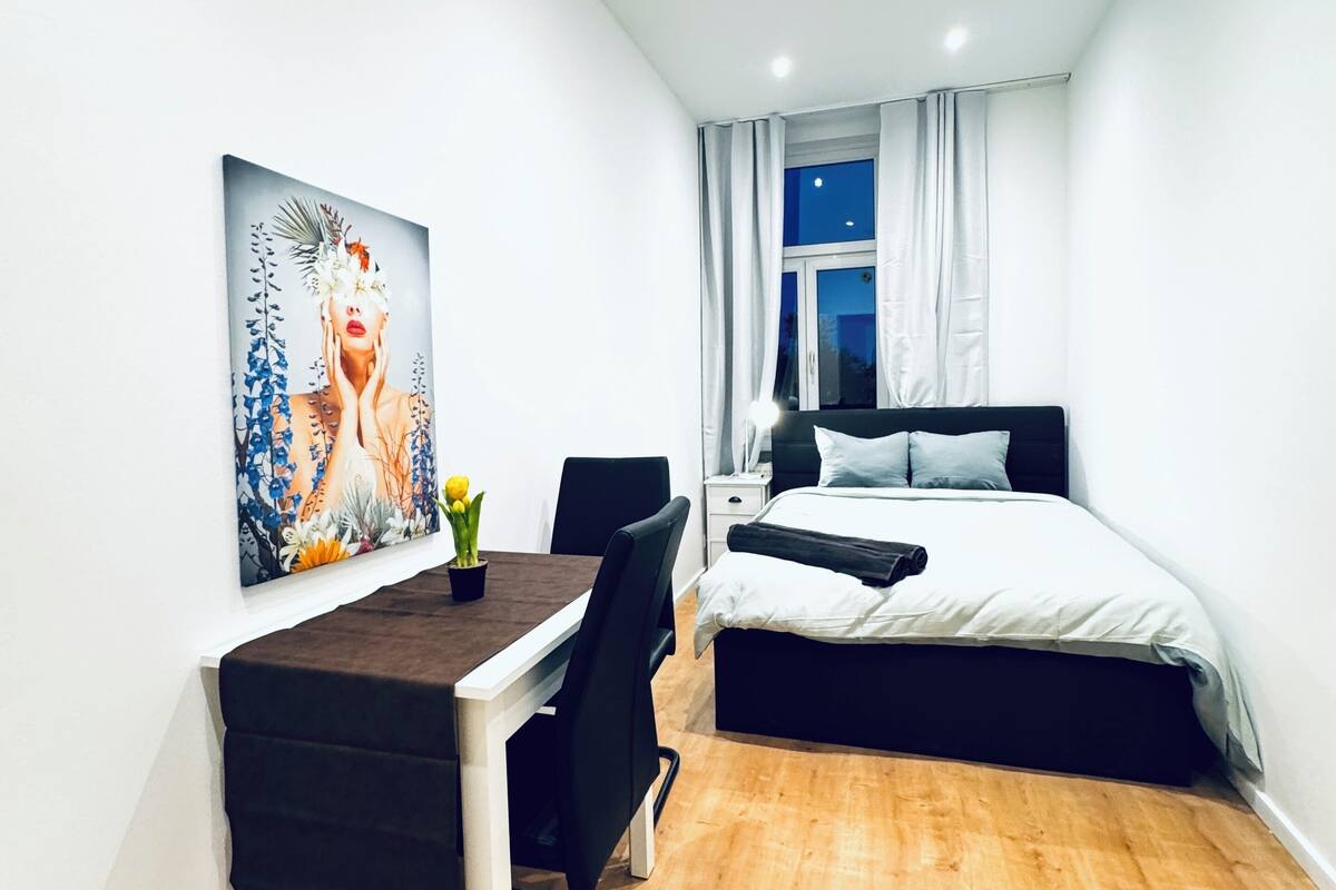 A modern bedroom with a bed, bedside table, and a painting on the wall.