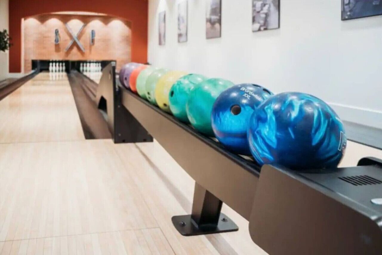 Une salle de bowling avec une rangée de boules de bowling colorées sur un présentoir.