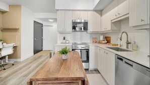 Een moderne keuken met witte kastjes, een houten eettafel en een inbouwoven.