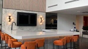 Een moderne keuken met een marmeren aanrechtblad, een ingebouwde televisie en een houten accentmuur.