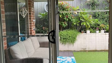 Step outside to a serene patio area with a comfortable sofa and lush greenery.
