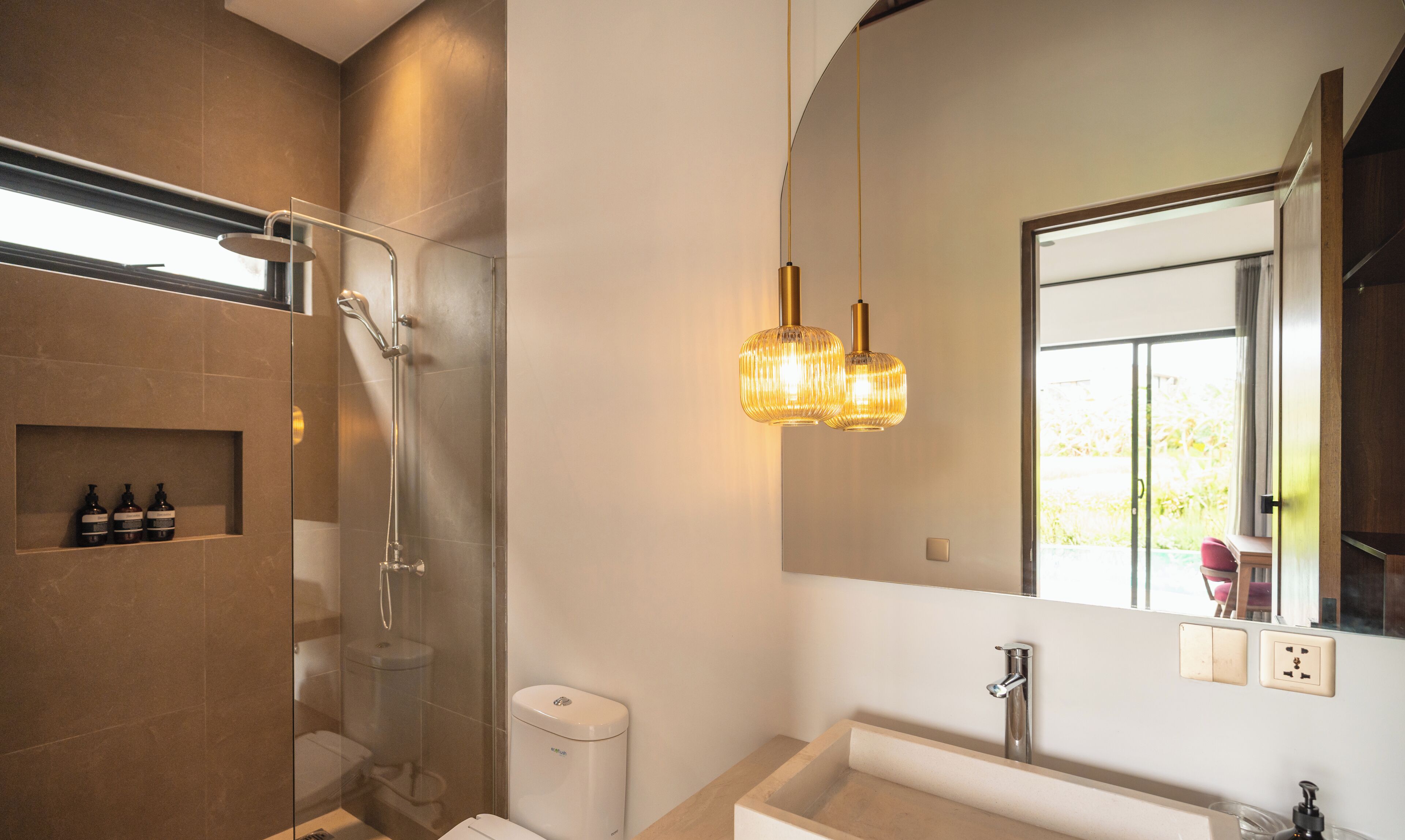 A modern bathroom with a glass-enclosed shower, a large mirror, and a pendant light.