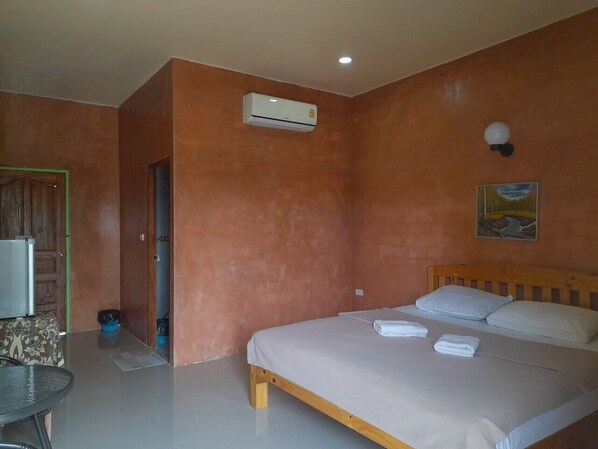 A bedroom with a bed, an air conditioning unit, a painting on the wall, and a door leading to another room. - Jayzada Fang Resort (Fang)