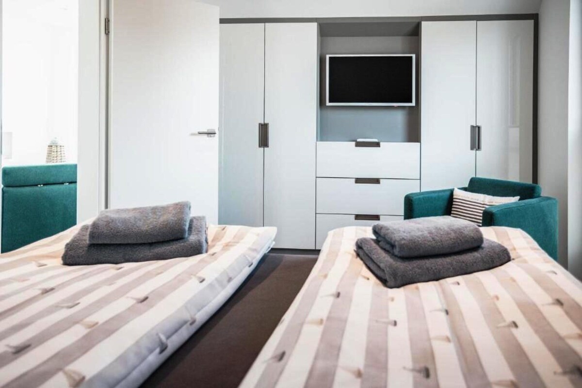 Een moderne hotelkamer met twee bedden, een televisie en een kledingkast.