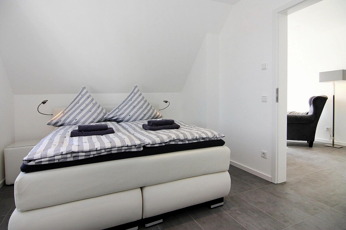 Une chambre à coucher moderne avec un lit, des oreillers et une chaise.