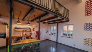 A spacious kitchen with a wooden ceiling, a green bench, and a window with a view.