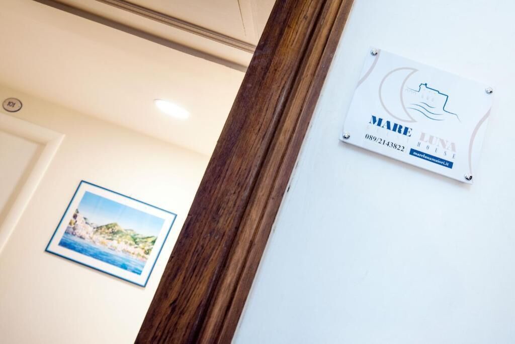 Un letrero de hotel con información de contacto y una foto enmarcada de un paisaje costero.