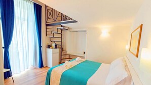 A hotel room with a bed, a desk, a chair, a staircase, and a wall-mounted shelf. - CVM Mare Luna Guesthouse (Maiori)