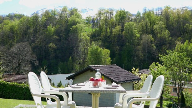 A table with chairs set outdoors, overlooking a forested hillside.