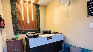 Un espace d’accueil comprenant un comptoir de réception, un canapé, un meuble et un ventilateur fixé au mur.
