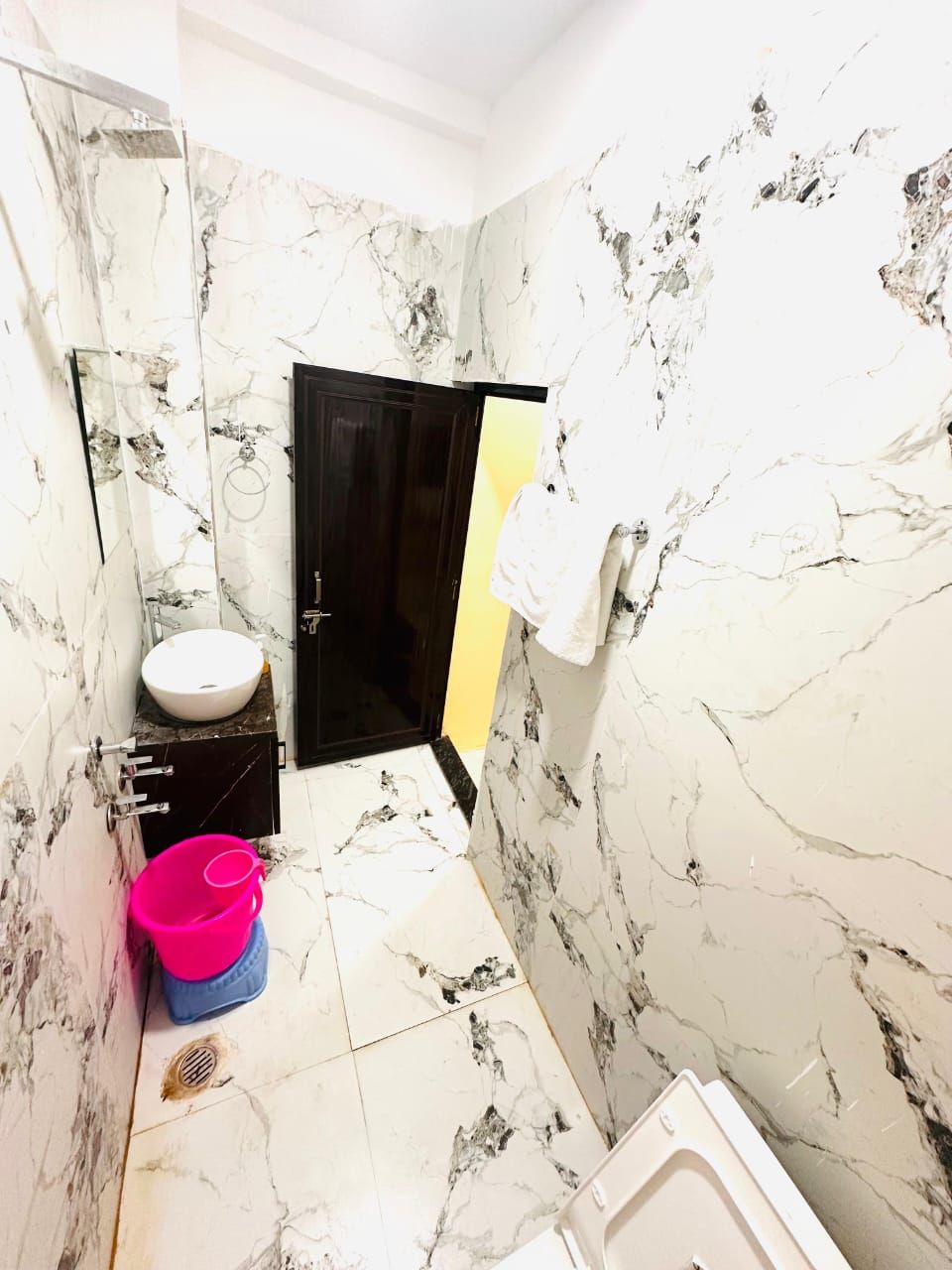Un baño con paredes de mármol, un lavamanos, un inodoro y una bañera.