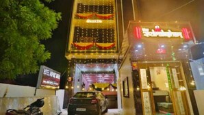 L’entrée d’un hôtel, avec un panneau indicateur, une voiture garée et une moto.