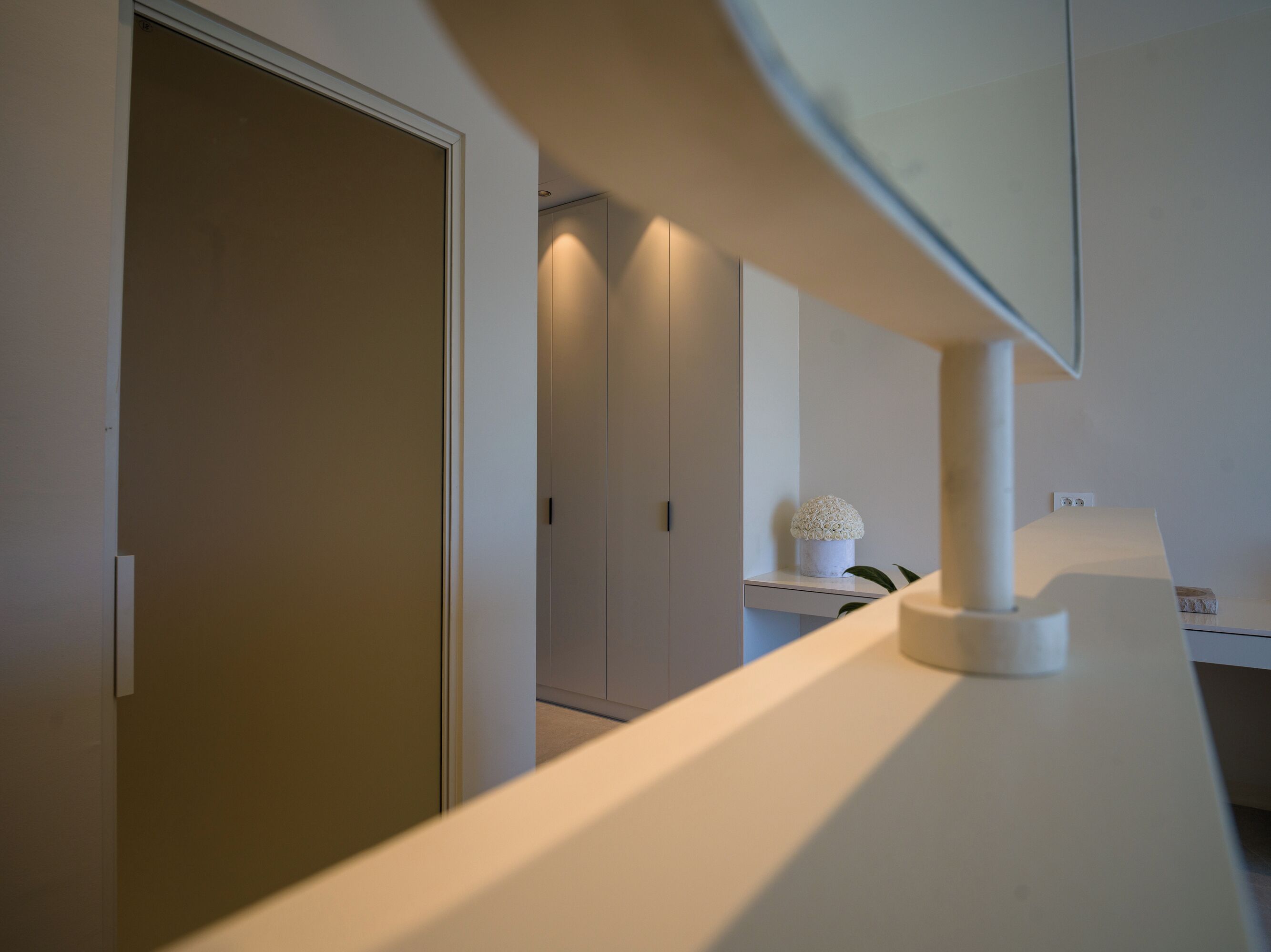 A modern interior with a white counter, a door, and a wall-mounted lamp.