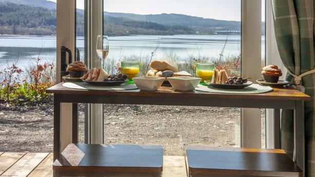 Une table de petit-déjeuner offrant une vue imprenable sur un lac et des montagnes.